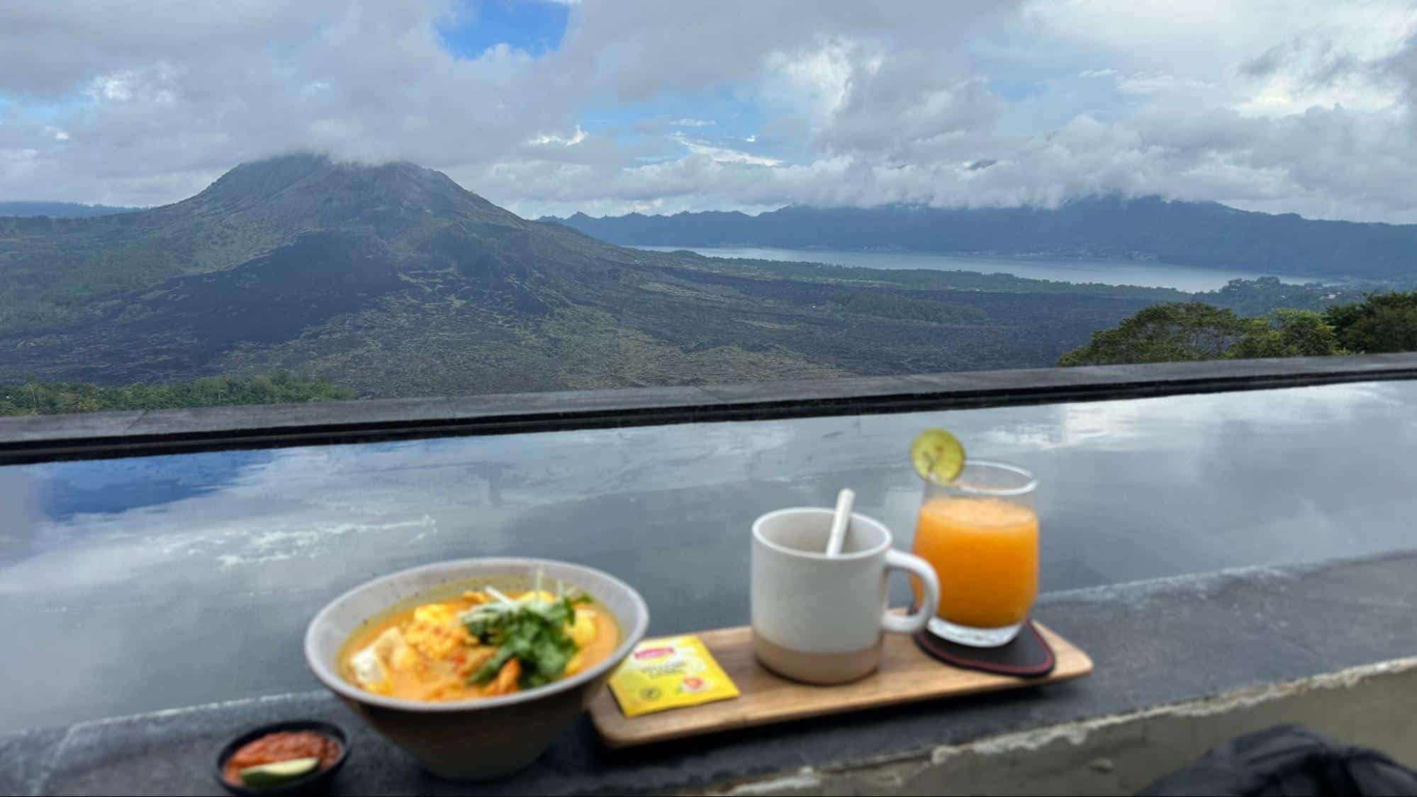 Breakfast with noodles, juice, and tea overlooking Mount Batur and Lake Batur in Bali