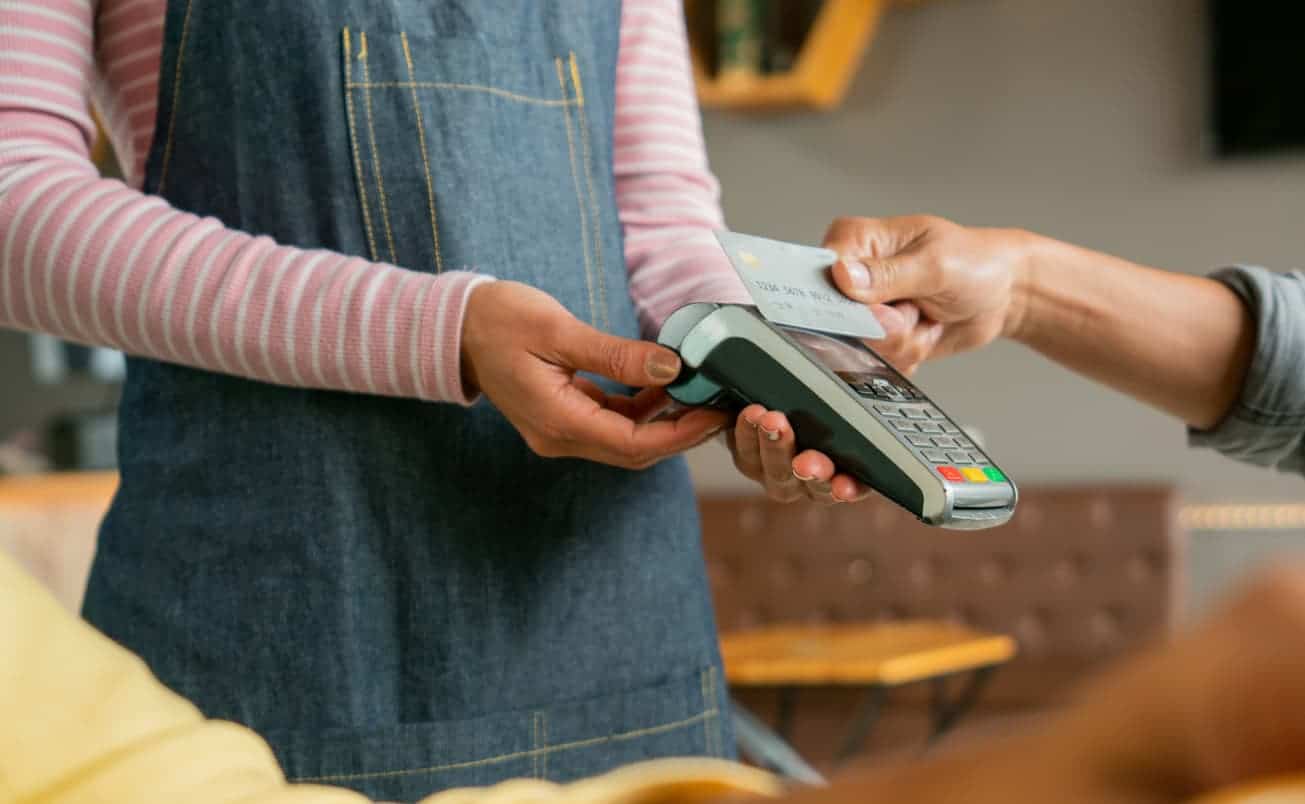 Customer making a contactless credit card payment in a cafe.