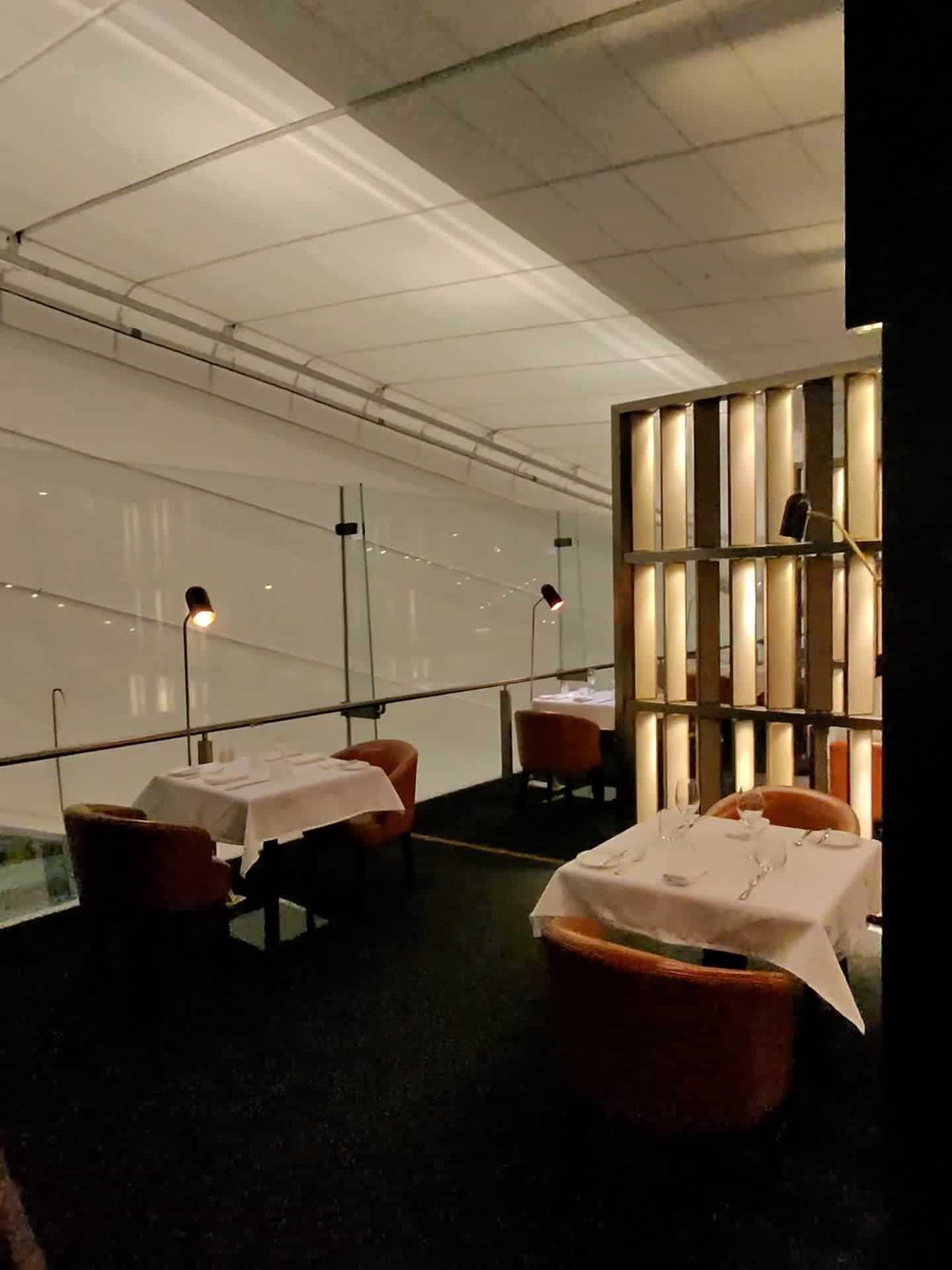 Private dining tables with soft lighting inside Etihad Airways First Class Lounge