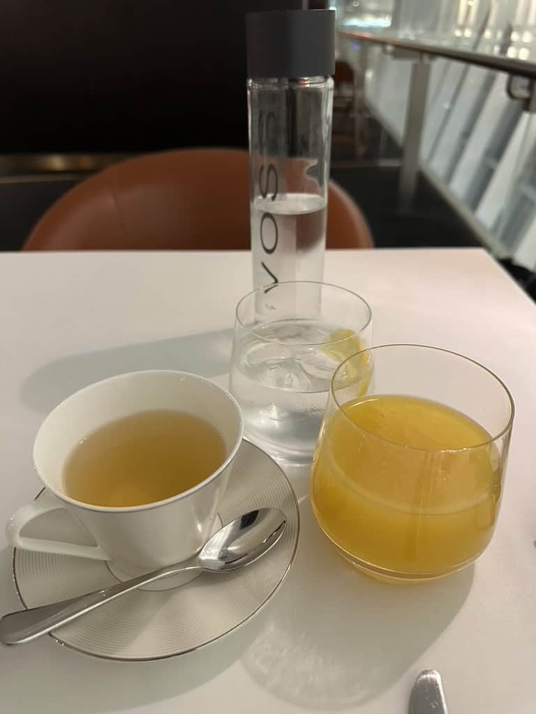 Tea, Voss water, and orange juice served at Etihad Airways Lounge table setting