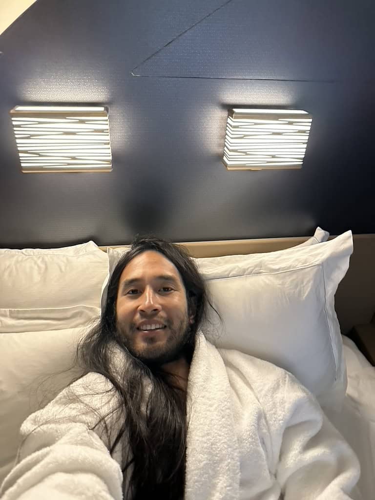 Passenger relaxing in Etihad Airways The Residence bed wearing a robe mid-flight