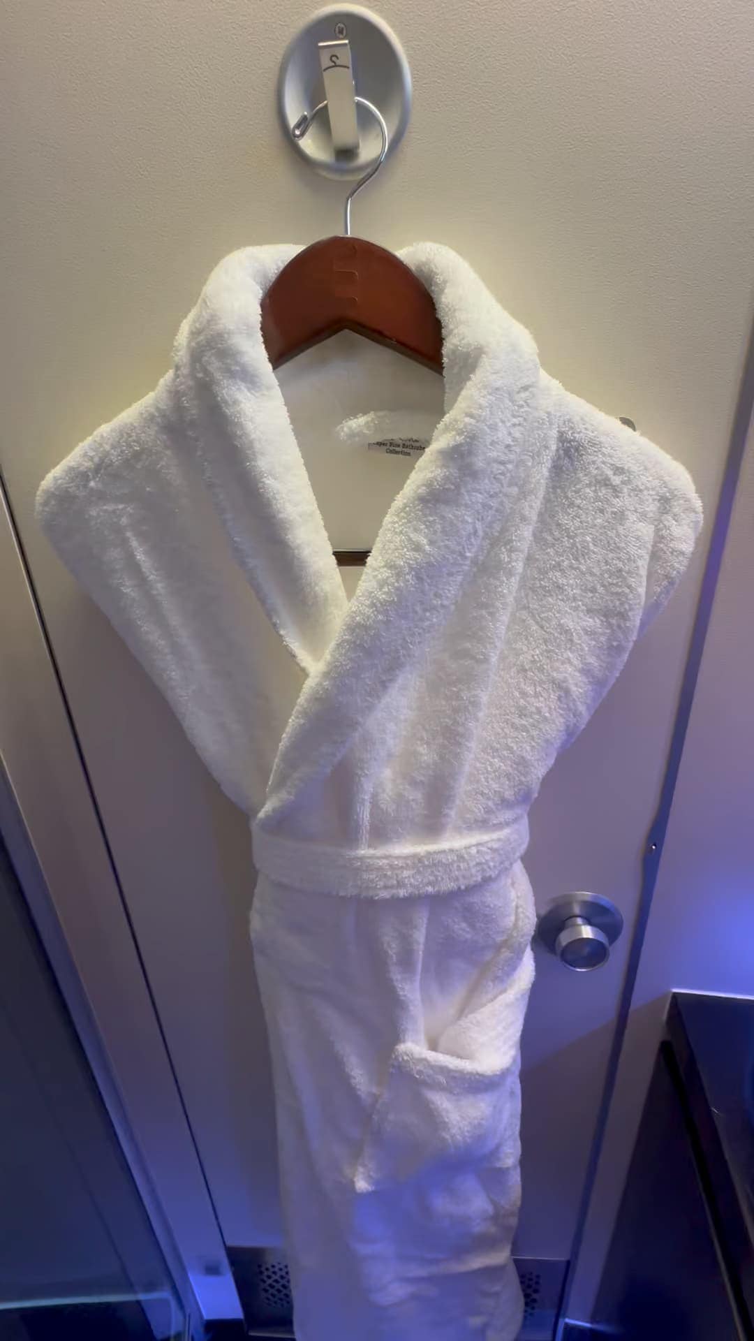 White luxury bathrobe hanging inside Etihad Airways The Residence bathroom