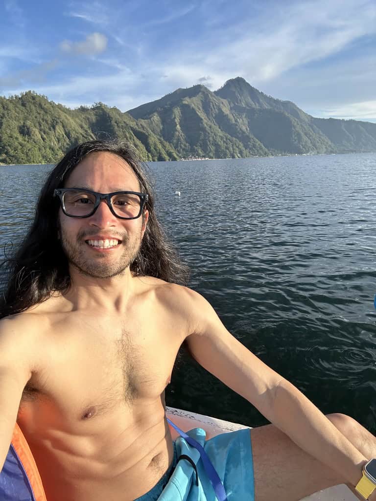 Traveler kayaking on calm Lake Batur surrounded by mountains in Bali