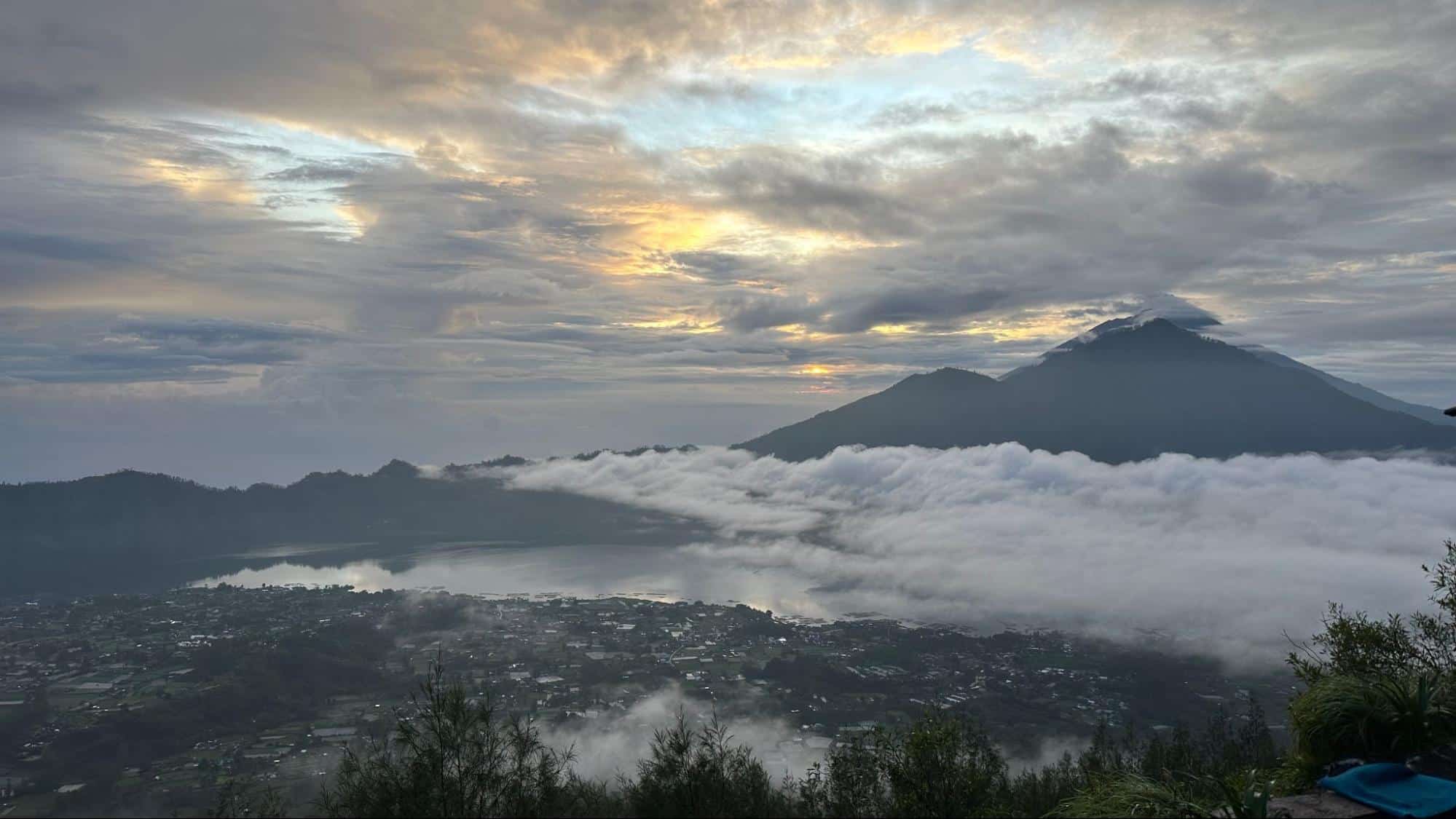 Breathtaking sunrise view over Mount Batur and Lake Batur with clouds drifting over the valley in Bali
