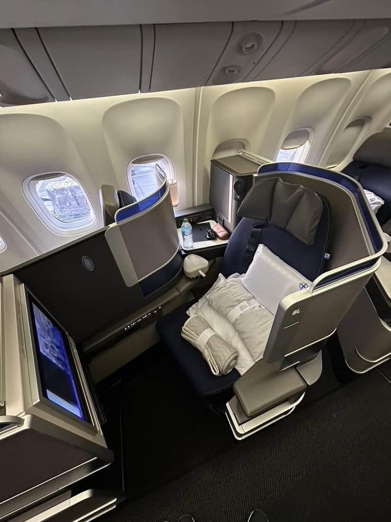 United Polaris business class seat 8L setup with bedding and an obstructed window view on a Boeing aircraft.