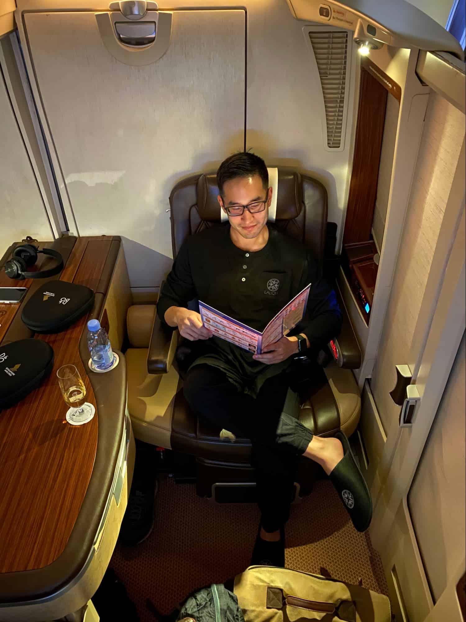 Traveler sitting in a first class airline seat reading the safety information card before takeoff.