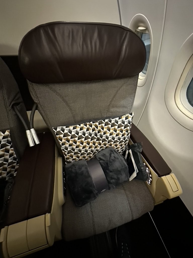 Singapore Airlines regional business class seat by the window with pillow and blanket placed on the seat