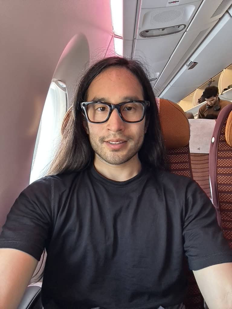 Passenger taking a selfie while seated in a Thai Airways economy class window seat.