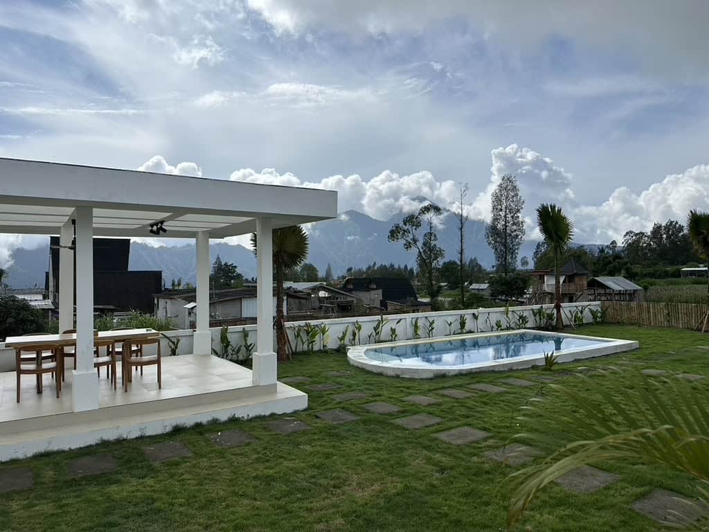 Outdoor dining area and swimming pool surrounded by mountain views at Volcano Garden View Bali