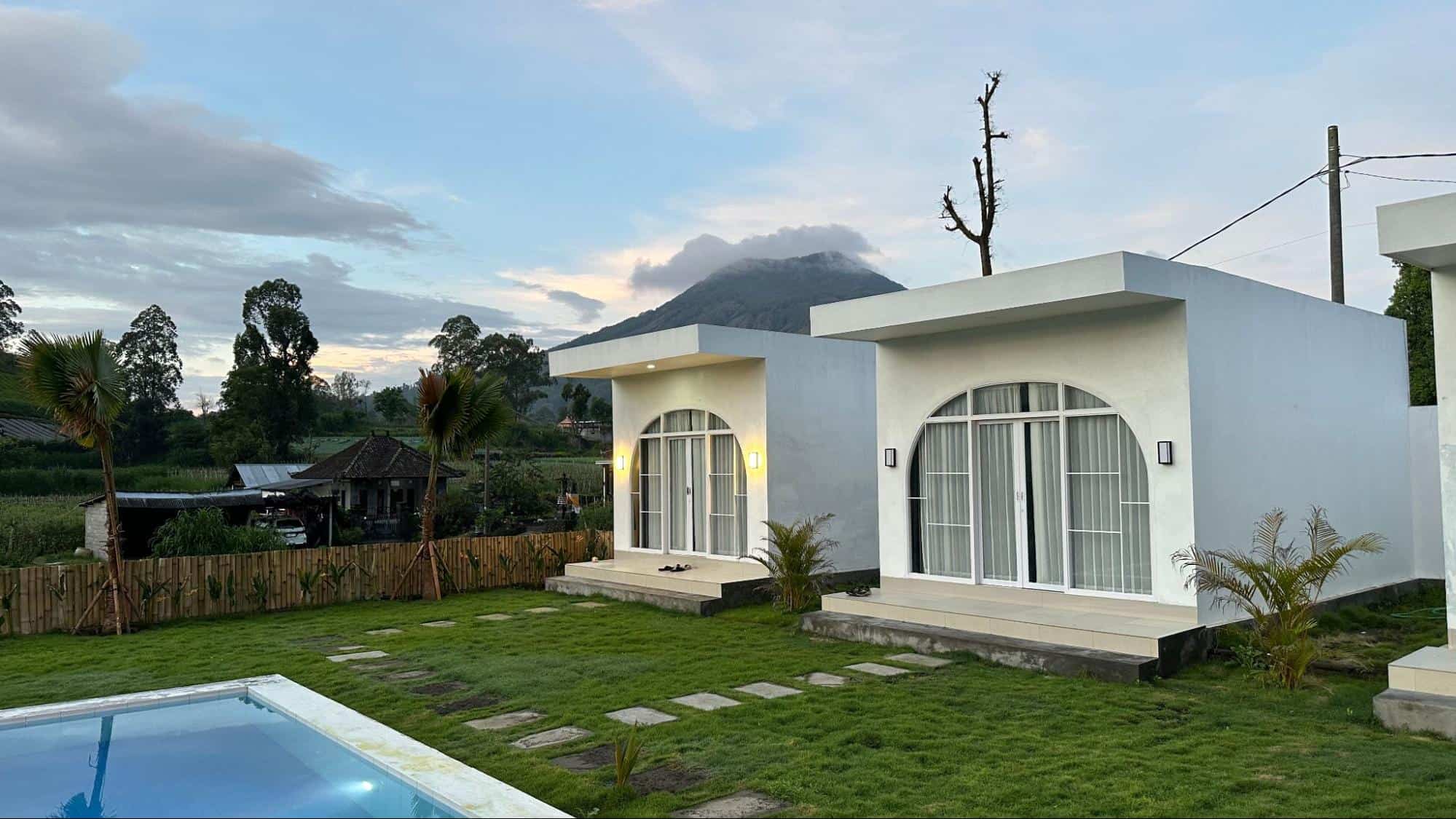 Modern white villas with swimming pool and mountain backdrop at Volcano Garden View Bali