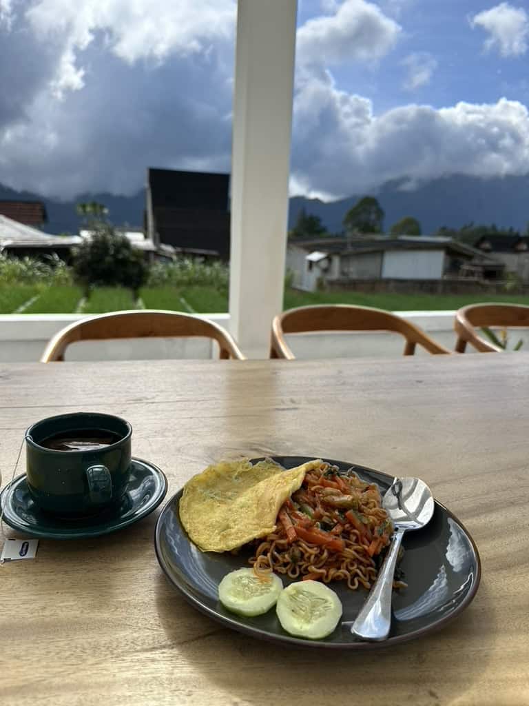 Breakfast plate of noodles and coffee with scenic mountain view at Volcano Garden View Bali