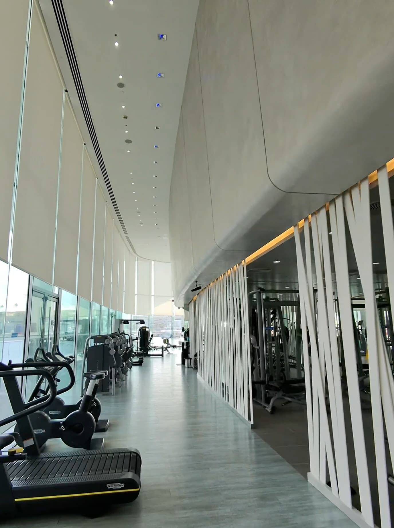 Modern gym at W Abu Dhabi with large windows and high ceilings overlooking Yas Marina