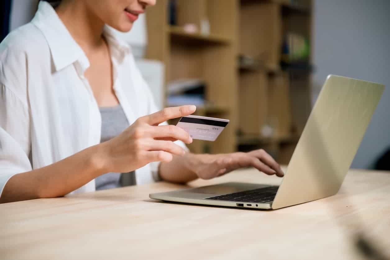 Woman making an online purchase with a credit card using her laptop at home