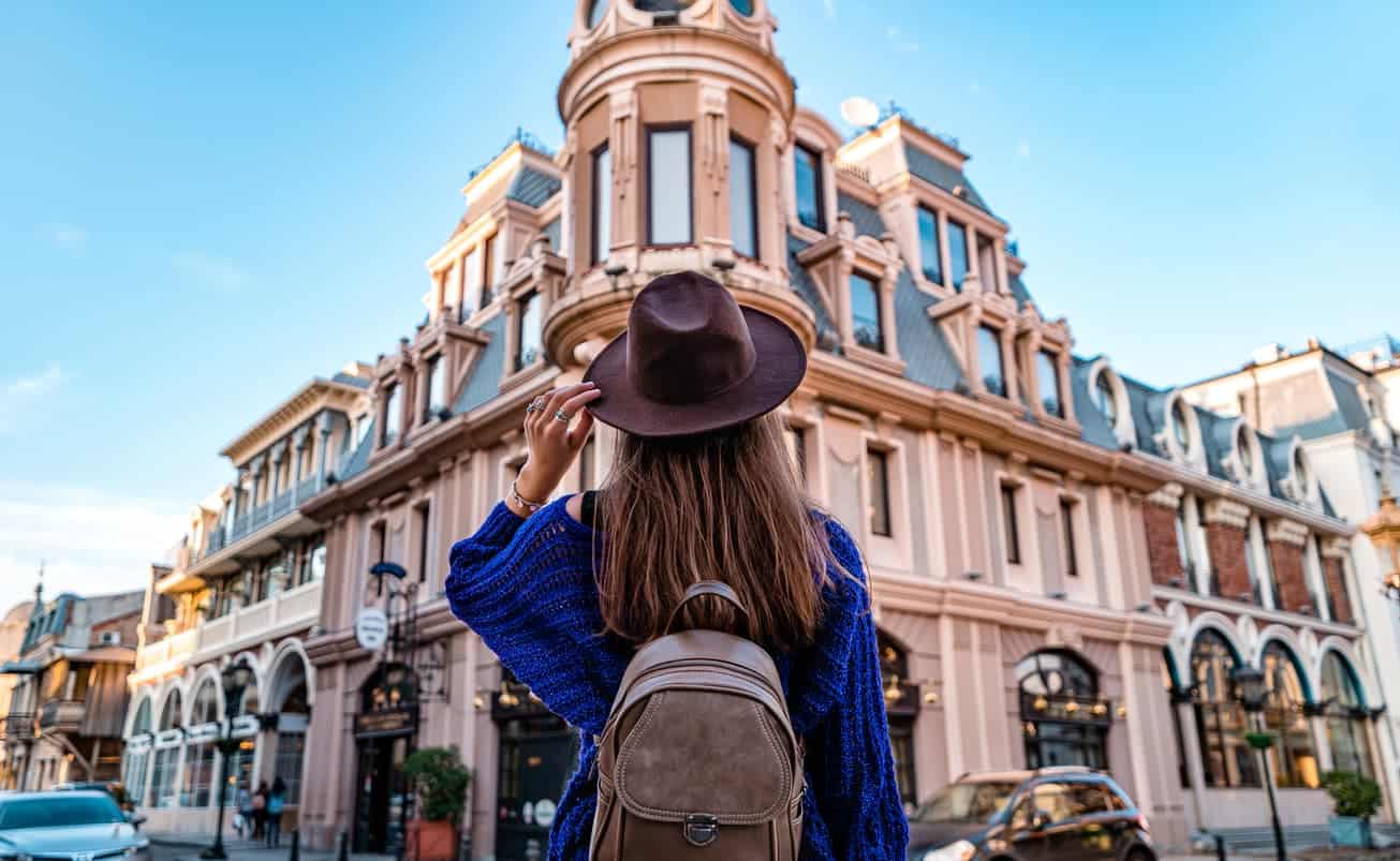 woman wearing a hat and backpack exploring a European city during solo travel