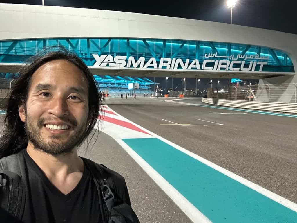 Visitor smiling at Yas Marina Circuit under bright night lights in Abu Dhabi