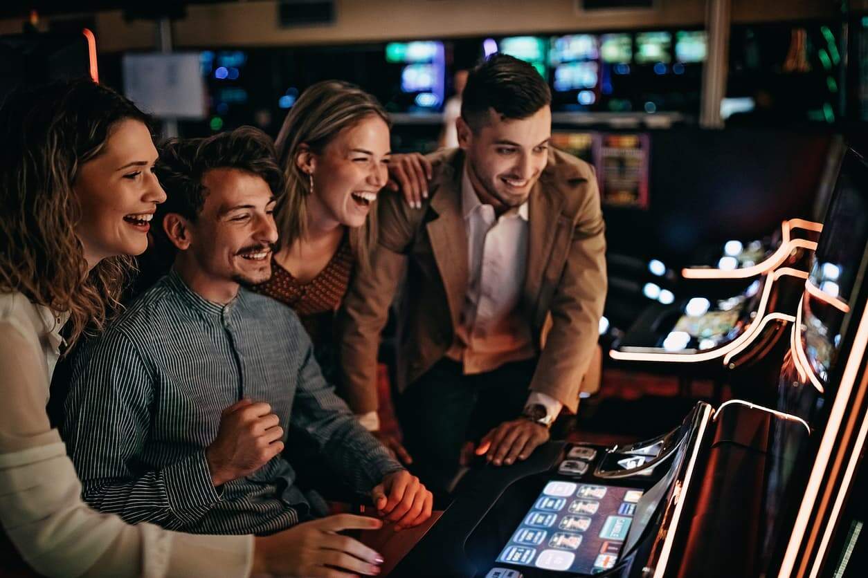 Group of friends laughing and playing together at a casino slot machine.