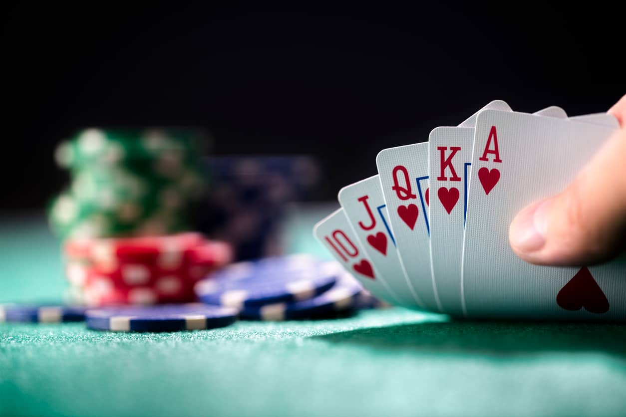 close-up of a winning poker hand with heart cards and colorful casino chips on a green table