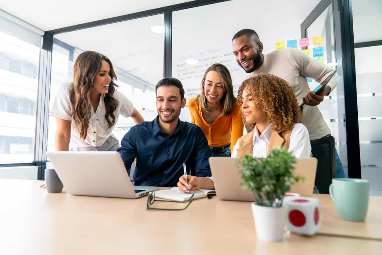 diverse coworkers collaborating around laptops during a team meeting in a modern office