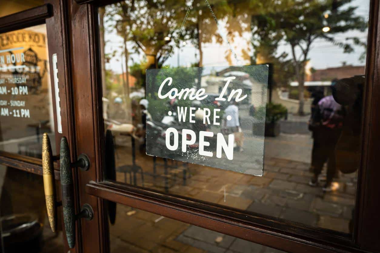 storefront glass door with a hanging “Come in, we’re open” sign