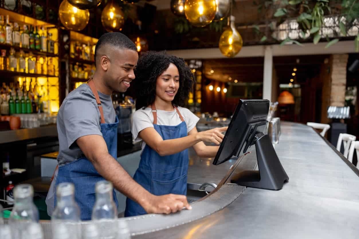 restaurant employees learning to use POS system behind the bar