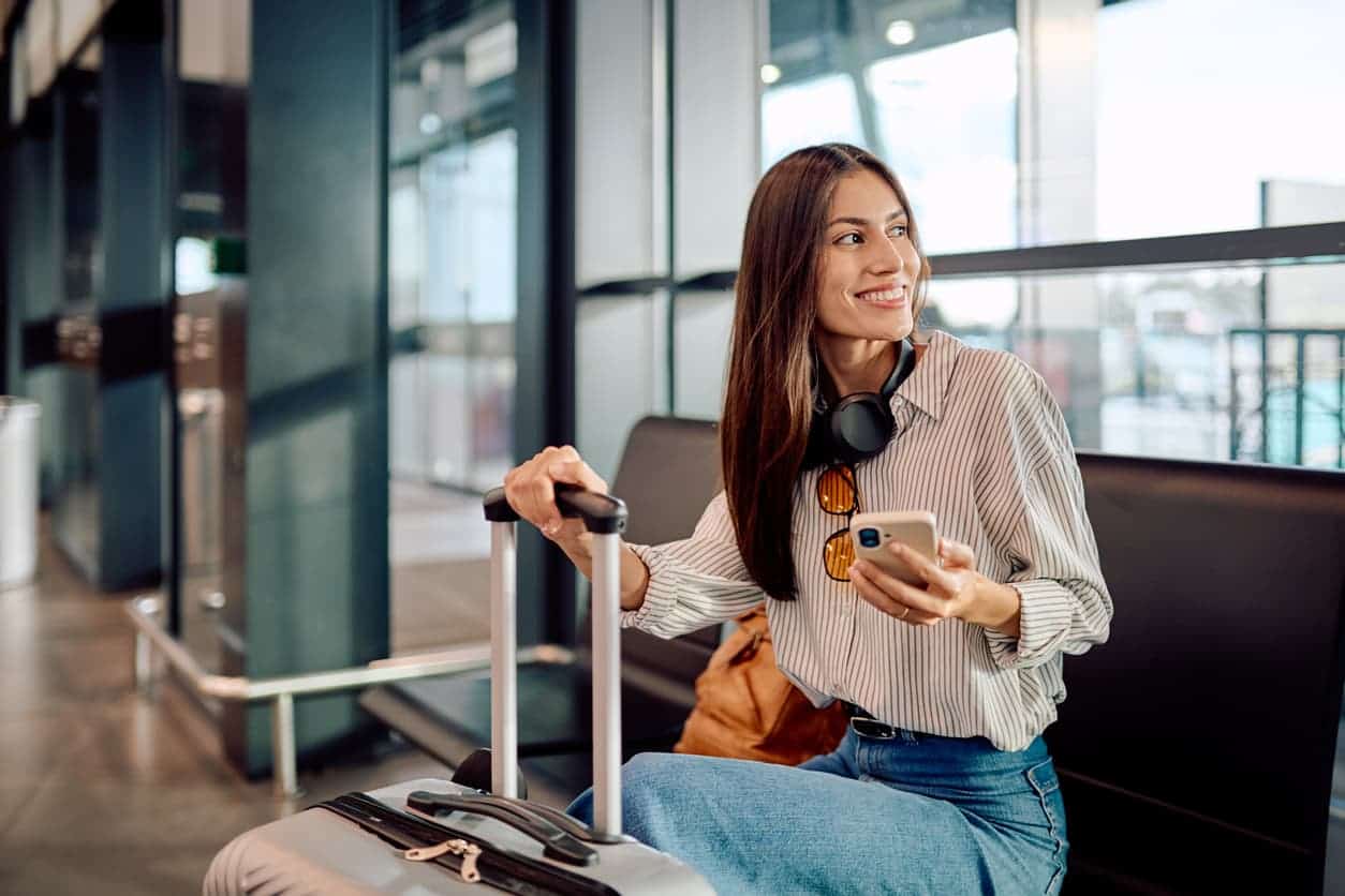 woman sitting at airport with suitcase
