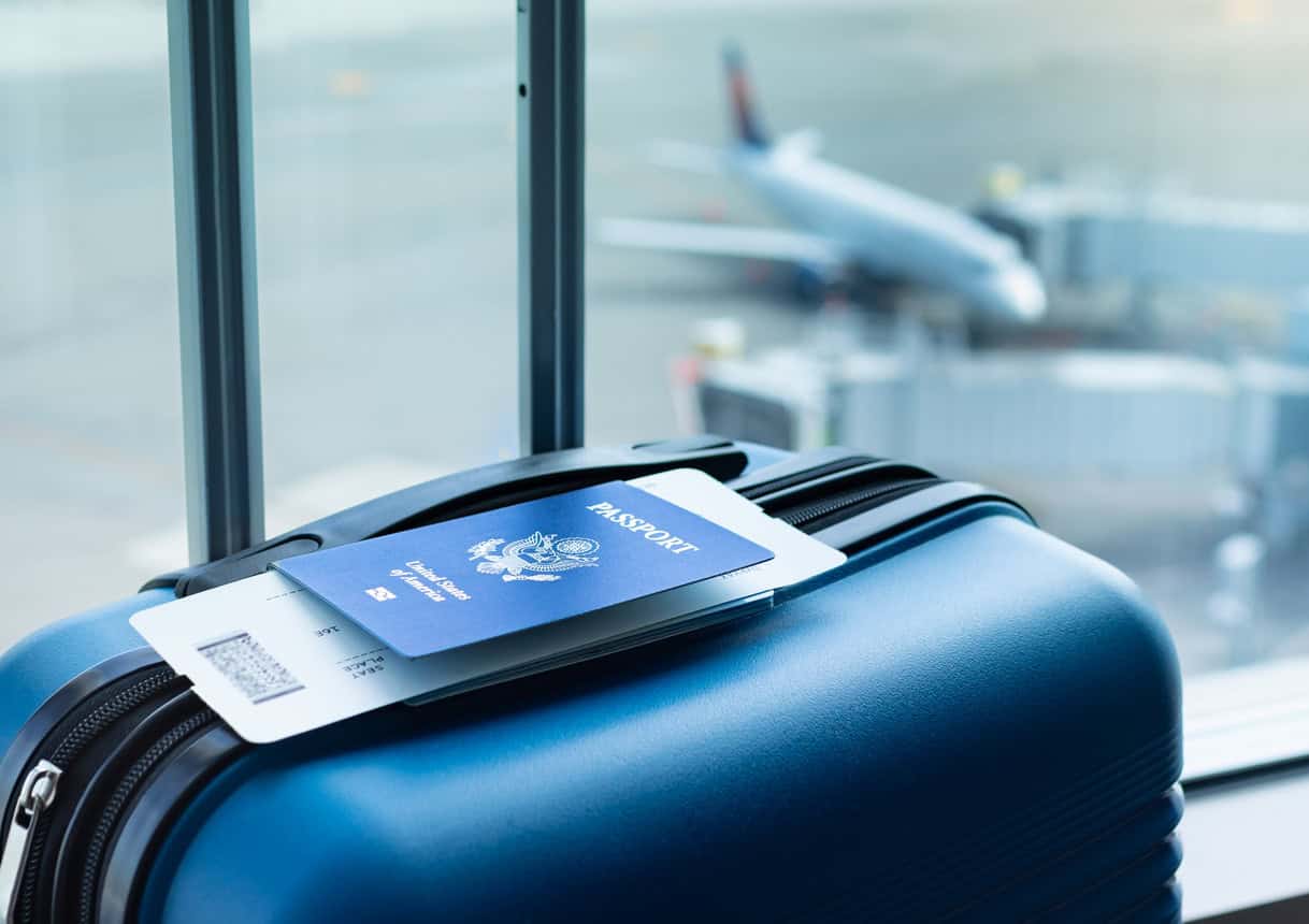 Passport and boarding pass resting on carry-on luggage at the airport before a rewards-funded flight.