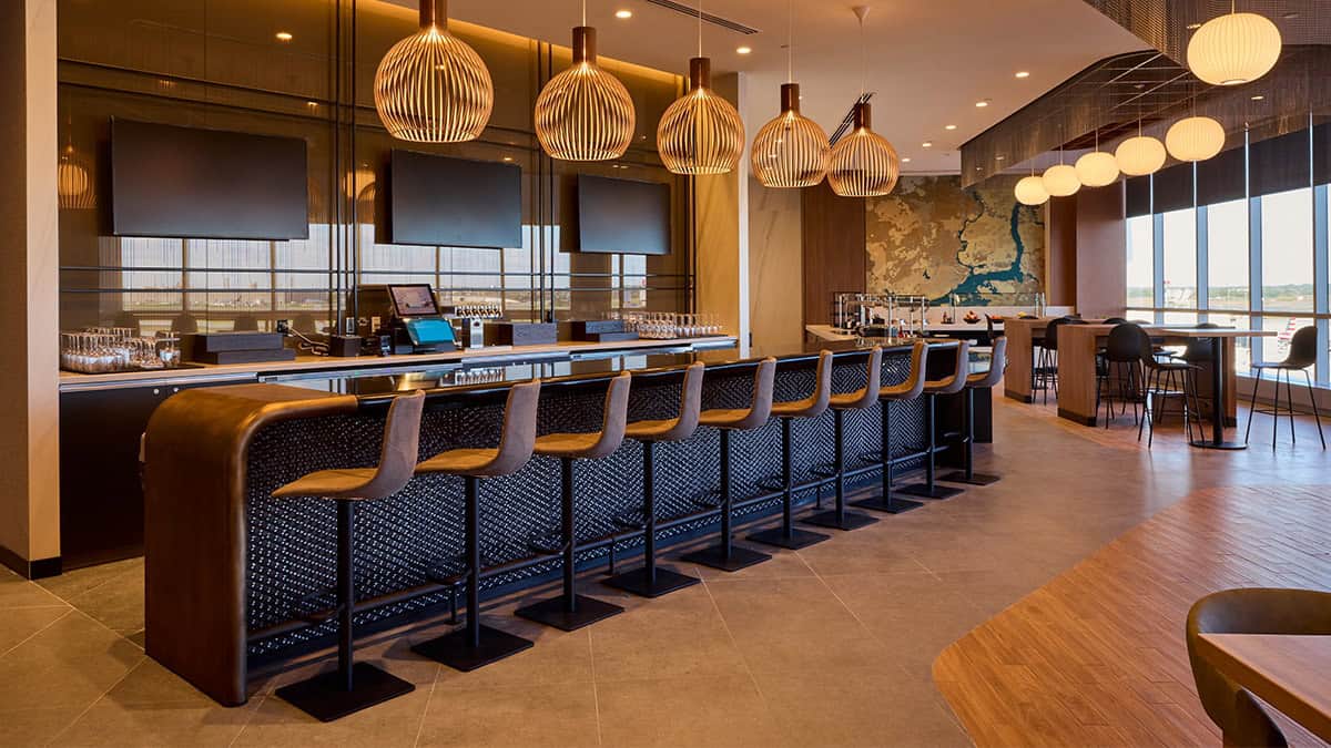 Bar area inside the American Airlines Admirals Club at Philadelphia International Airport, featuring modern seating, warm pendant lighting, and a full-service drink counter.