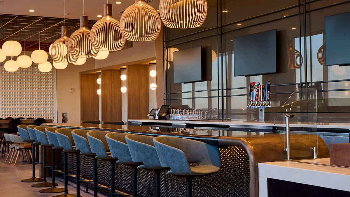 Bar area inside the American Airlines Flagship Lounge at Philadelphia International Airport, featuring modern seating, pendant lighting, and premium drink service.