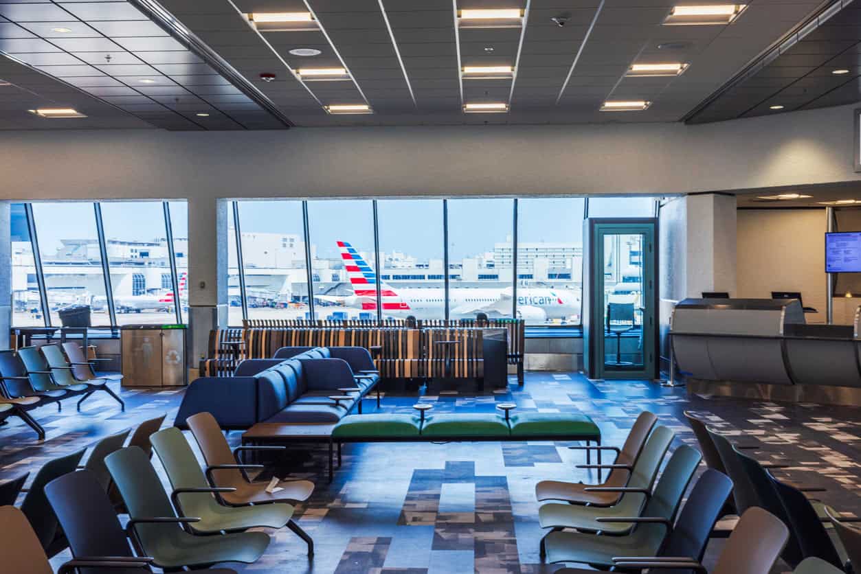 Empty airport terminal seating area with large windows overlooking airplanes parked at the gate.