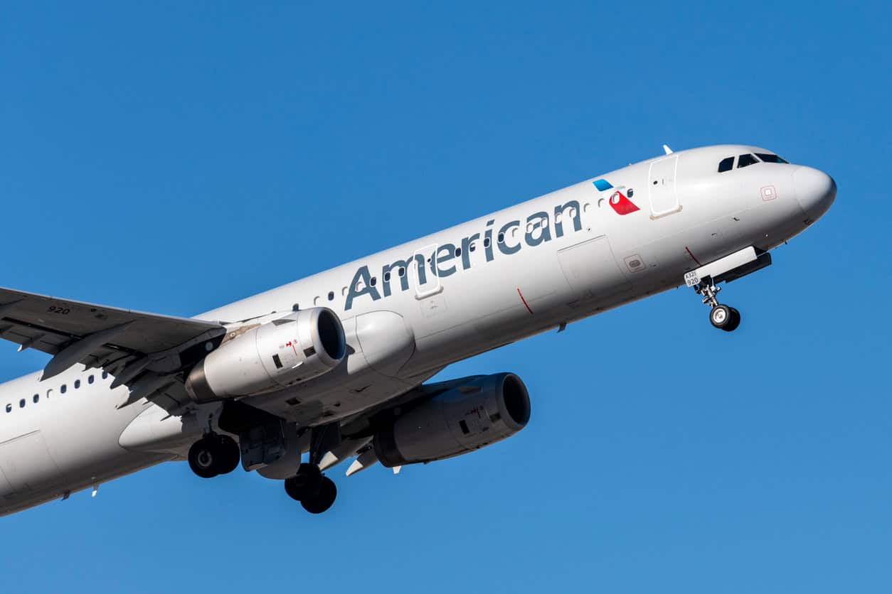 American Airlines airplane climbing after takeoff against a clear blue sky.