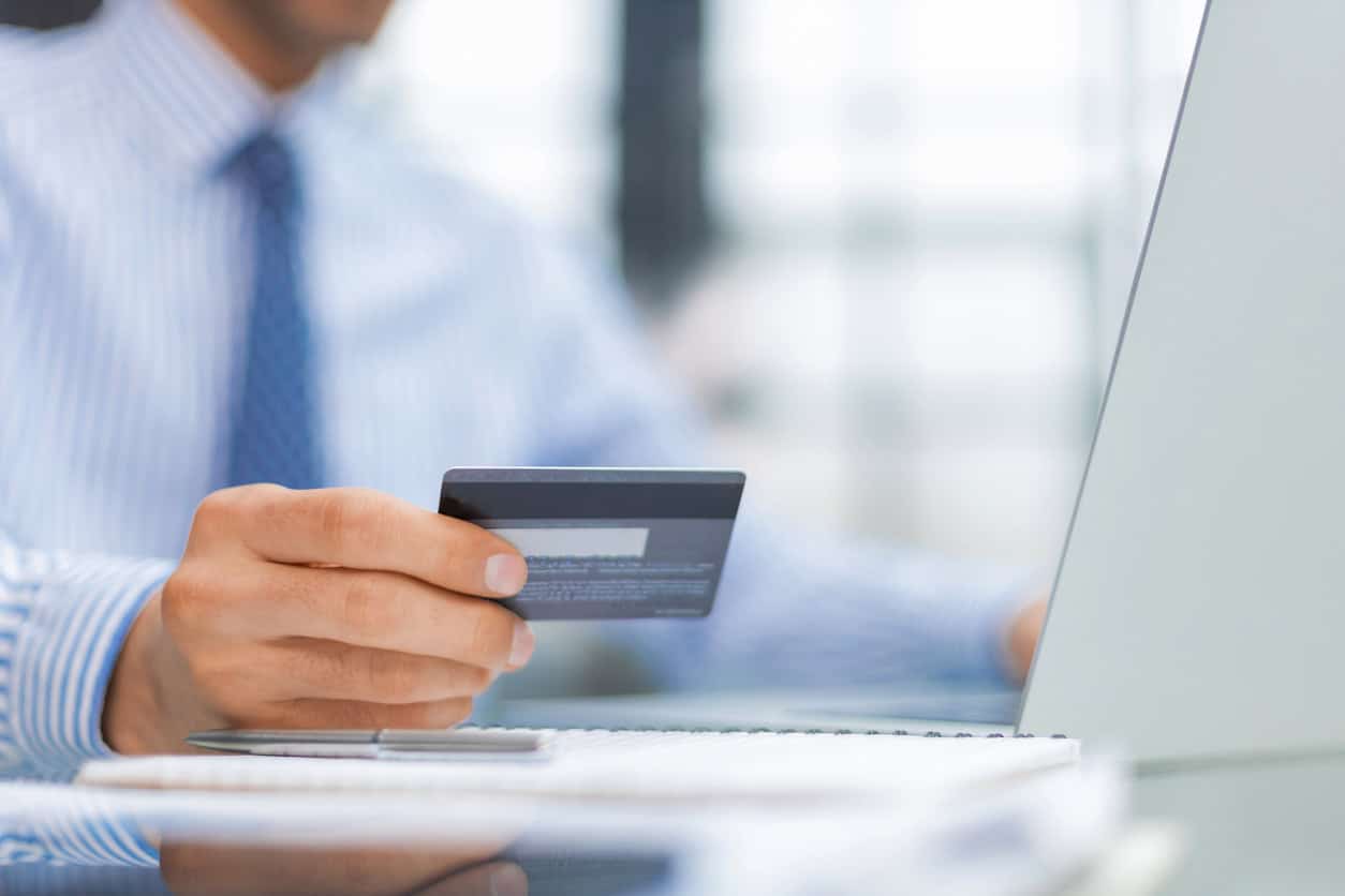 Business professional holding a credit card while making an online payment on a laptop