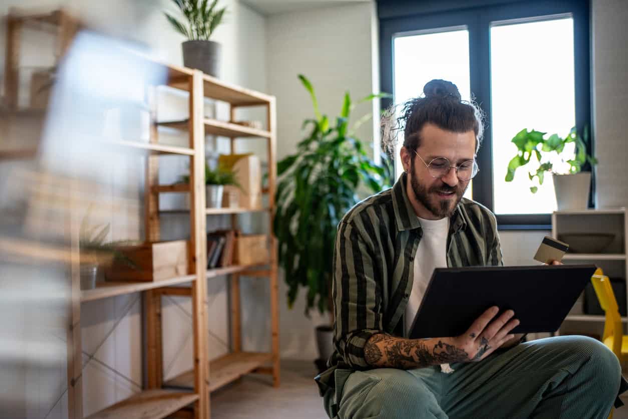 Business owner reviewing an online purchase on a tablet while holding a credit card in a home office