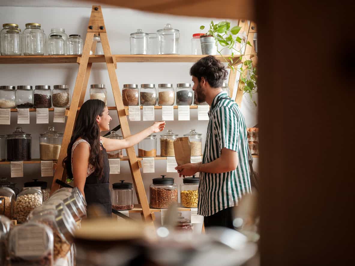 Small business owner assisting a customer with a purchase inside a bulk goods or zero-waste shop