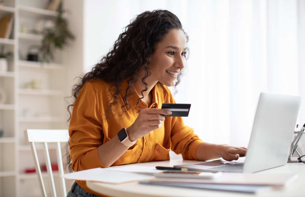 Small business owner making an online purchase at a laptop using a credit card in a home office