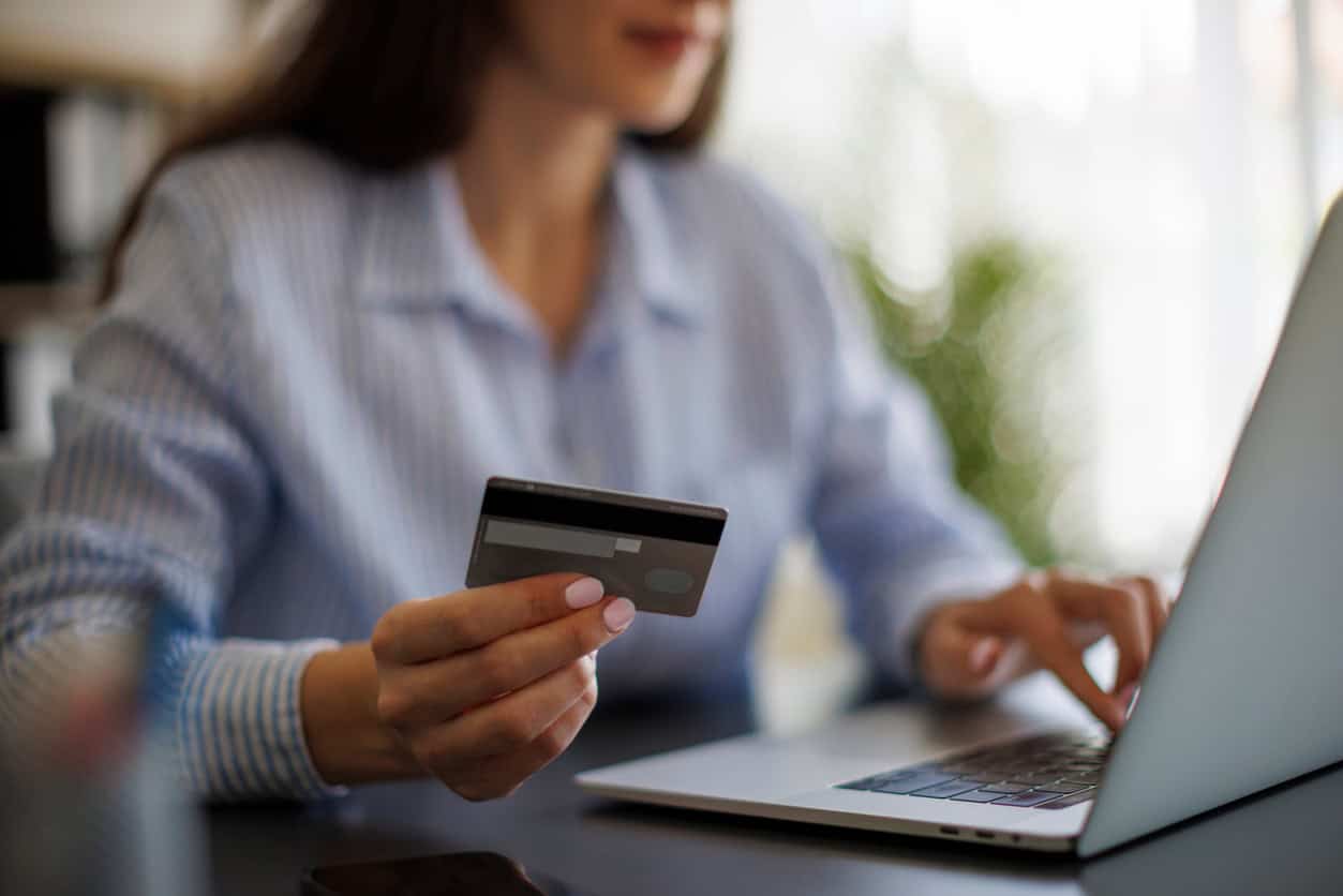 Woman entering credit card details on a laptop to make an online payment