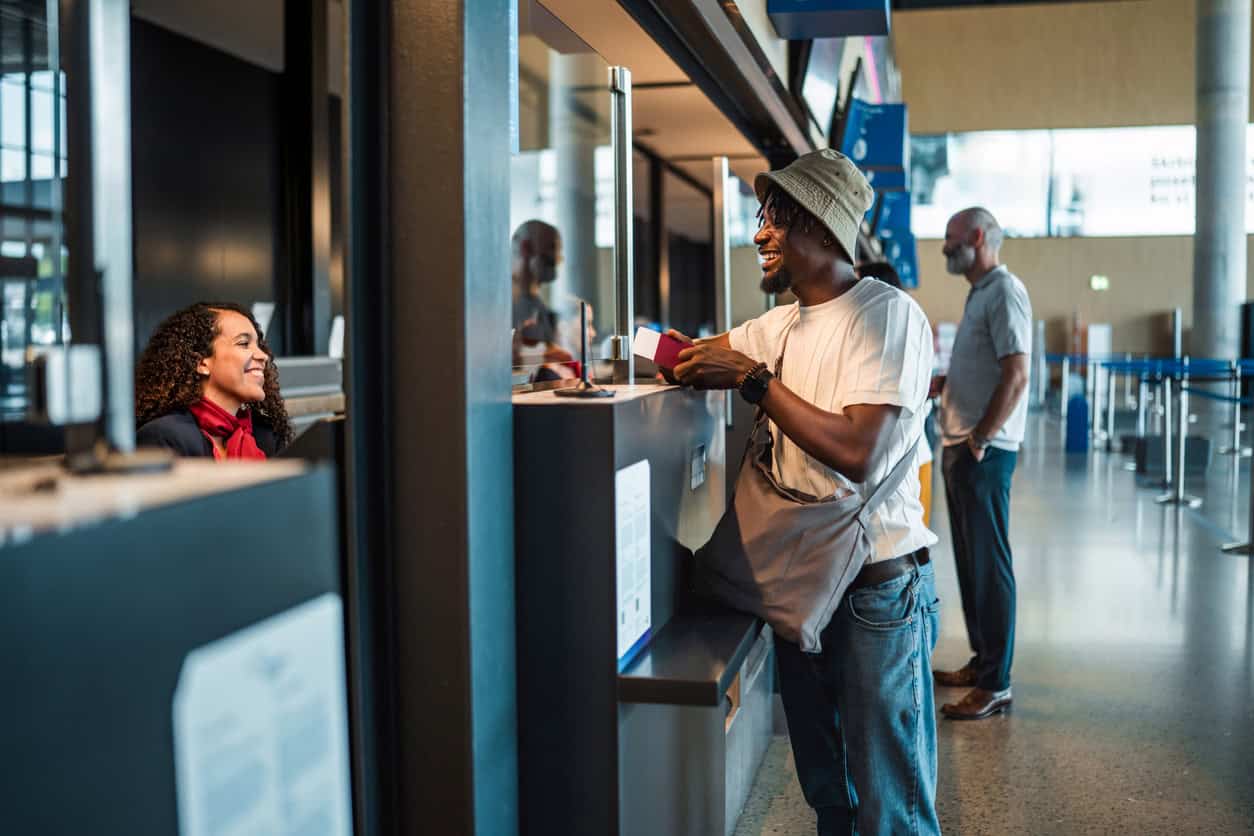 Traveler smiling while checking in at an airport counter, interacting with airline staff and highlighting service quality and customer experience.