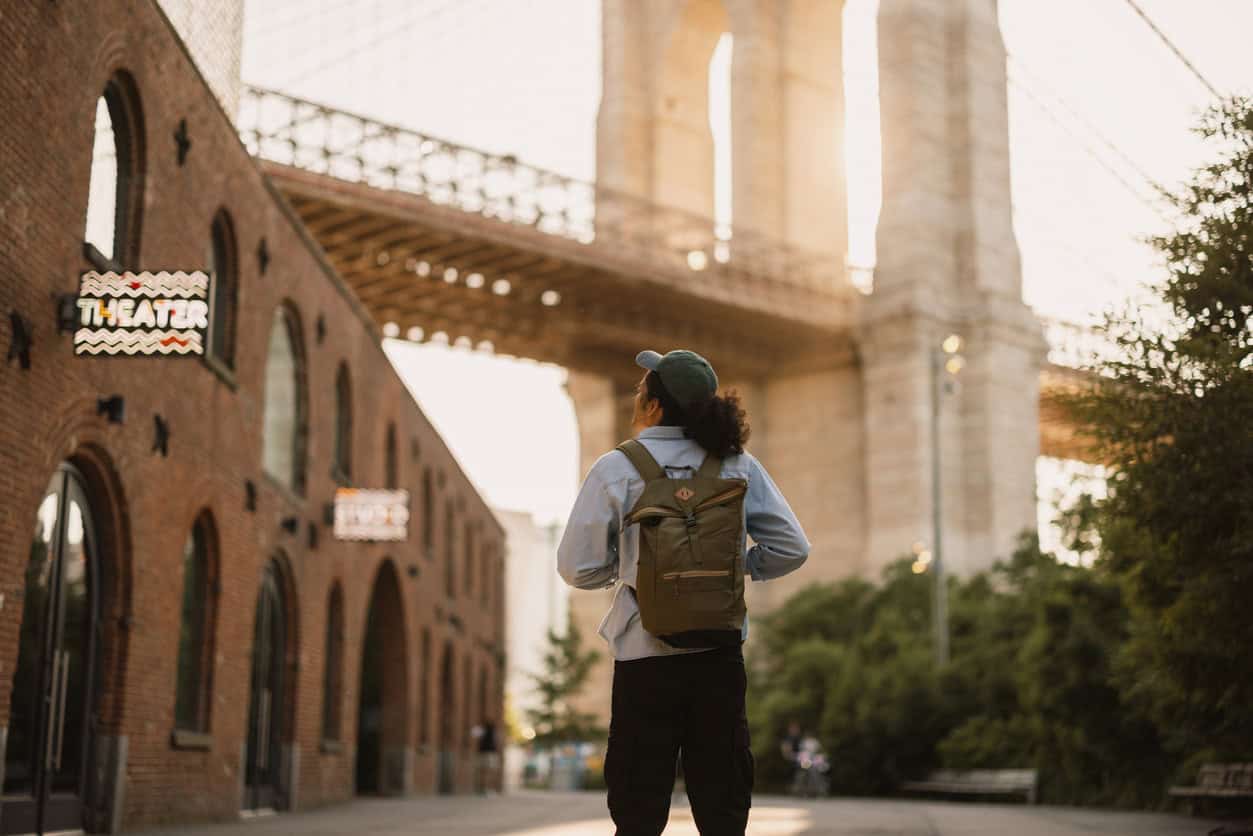 Traveler standing in DUMBO Brooklyn near the Brooklyn Bridge at sunset in New York City