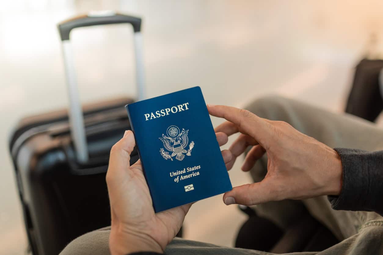 Traveler holding a United States passport with carry-on suitcase