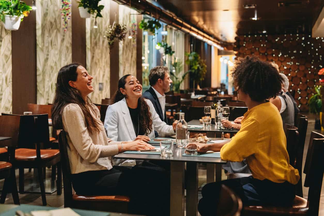 Group of friends laughing and enjoying dinner together at a restaurant during a night out