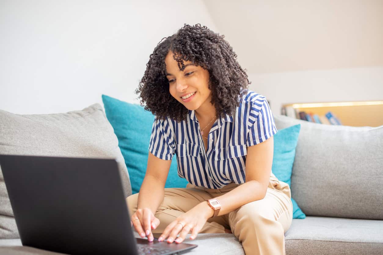 Woman using laptop at home checking travel deals and award alerts online