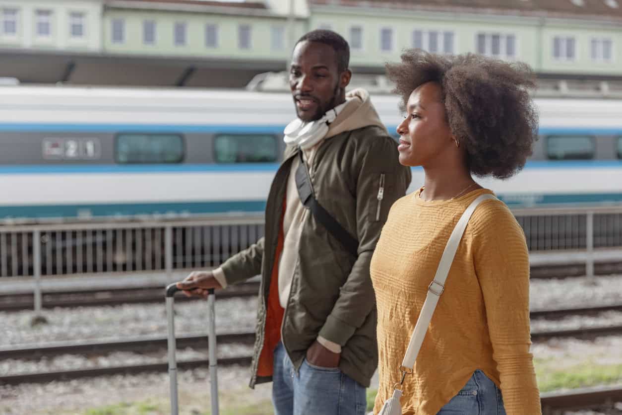 Couple walking through a train station with luggage, representing travel using points and miles rewards