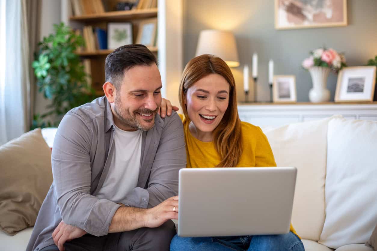 Couple using laptop at home reviewing credit card benefits and tracking rewards