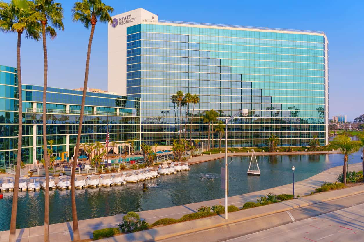 Hyatt Regency waterfront hotel with palm trees and marina boats along scenic canal promenade