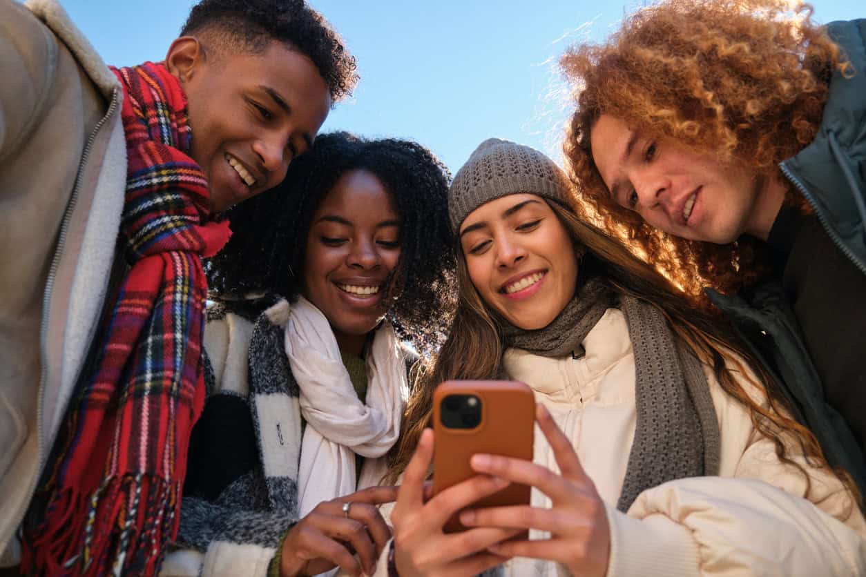 Group of friends looking at phone reviewing travel plans and points redemption details