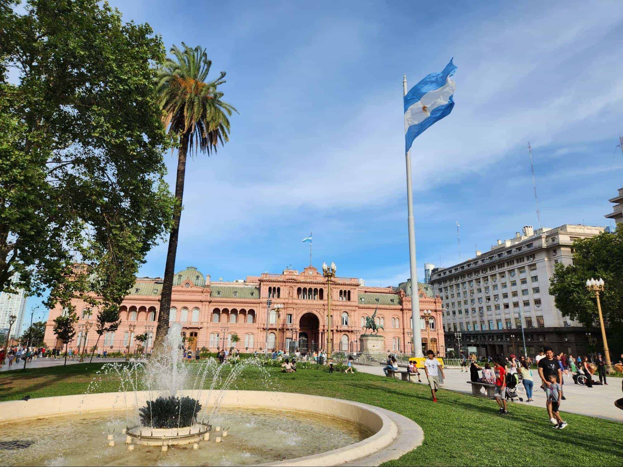 Casa Rosada, the presidential palace in Buenos Aires, Argentina, with the Argentine flag waving above a fountain and palm trees in Plaza de Mayo | Photo by Anya Kartashova