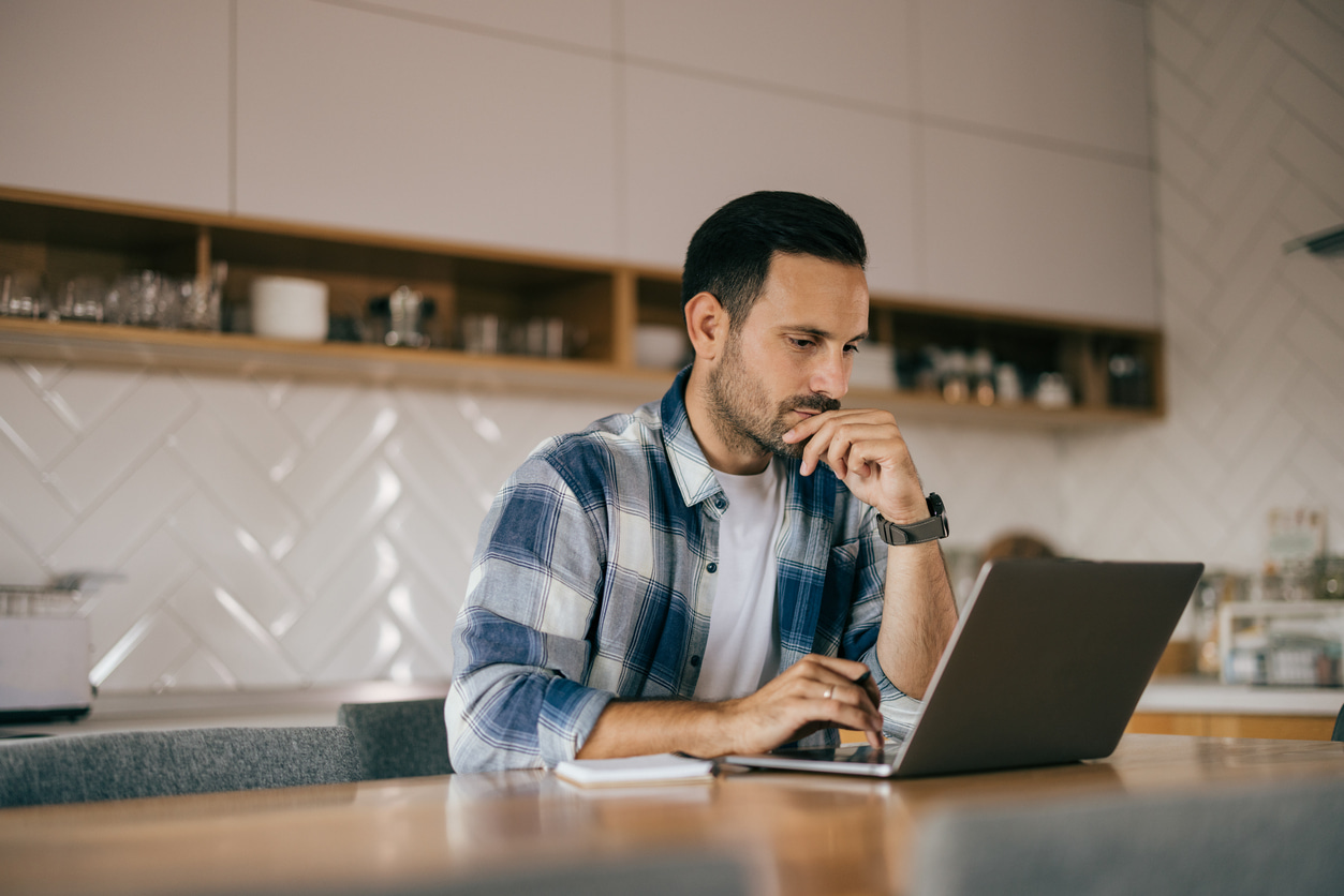 Concerned traveler using a laptop at home while reading disappointing news about an airline loyalty program change or devaluation announcement
