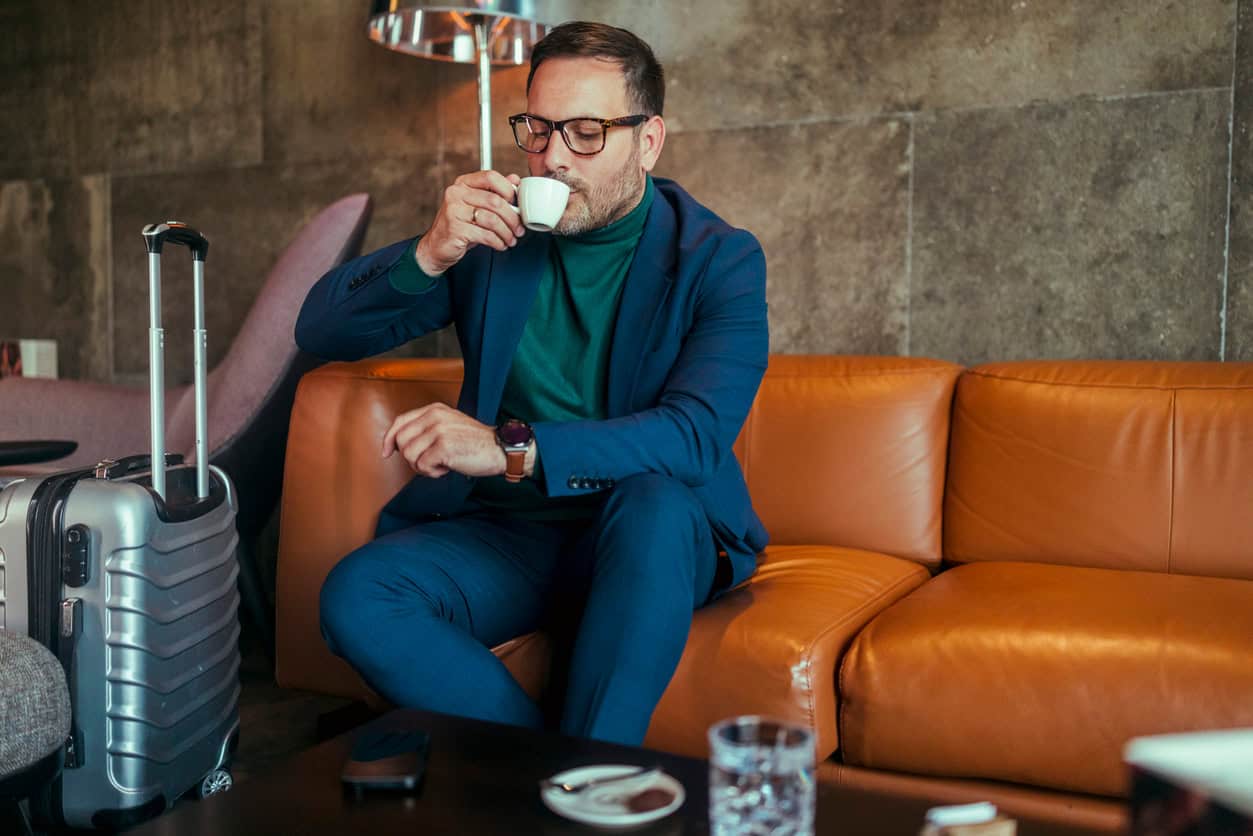 Traveler relaxing in an airport lounge with complimentary lounge access from a travel rewards credit card.