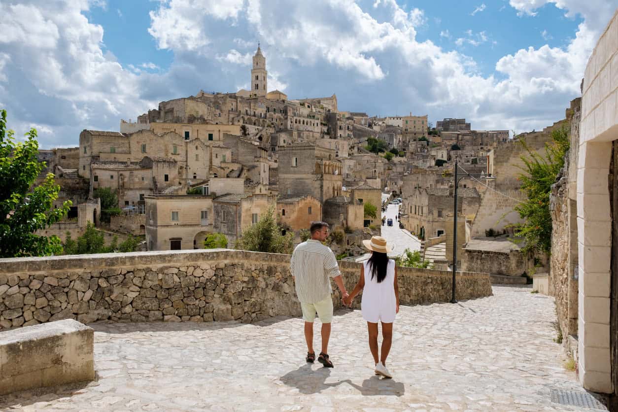 Travelers stroll through a historic European town with centuries-old stone architecture.
