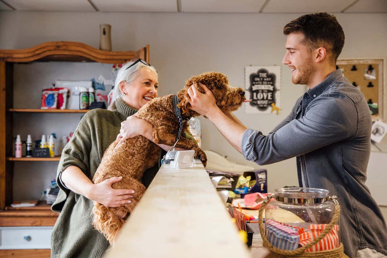 Small business owner assisting a customer with their dog at a local pet store.