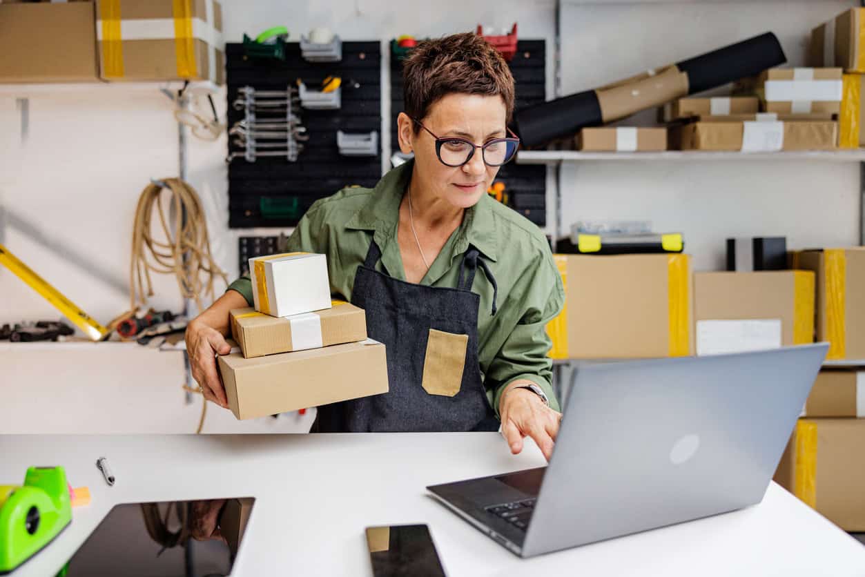 Small business owner organizing customer orders and managing shipments from a home workspace.